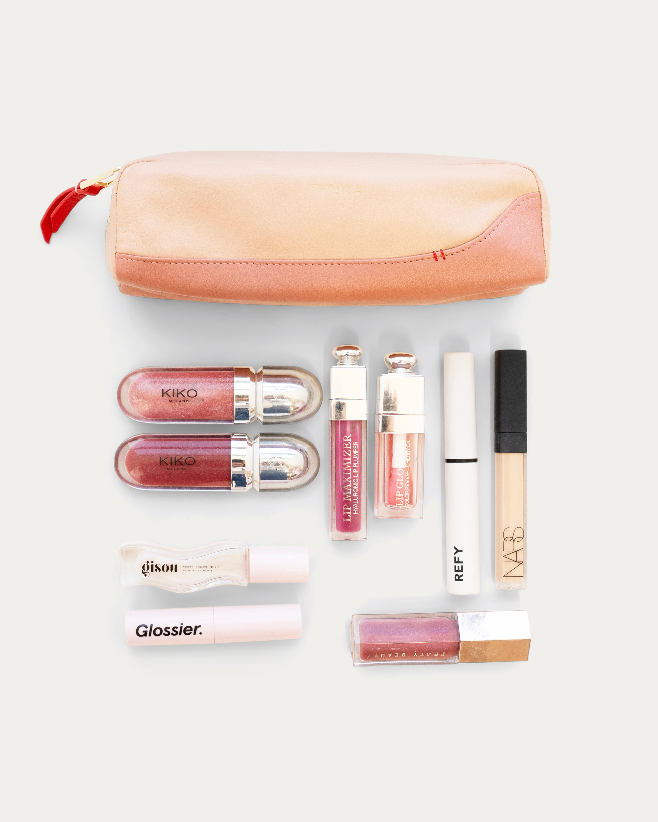 Set of lip products including lip glosses and a pouch on a white background