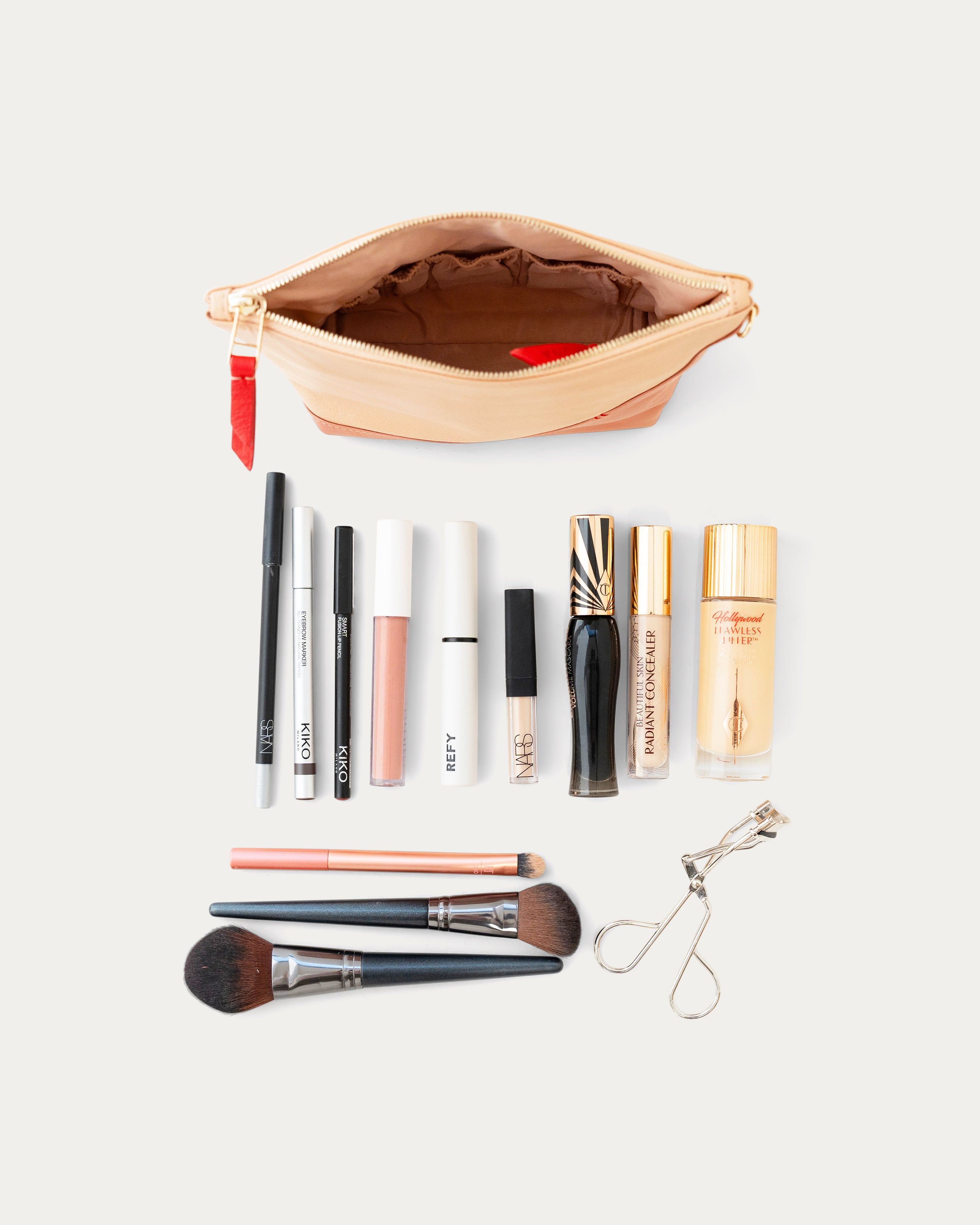 Makeup products including bottles, brushes, and a pouch on a white background - Kuwait bags 